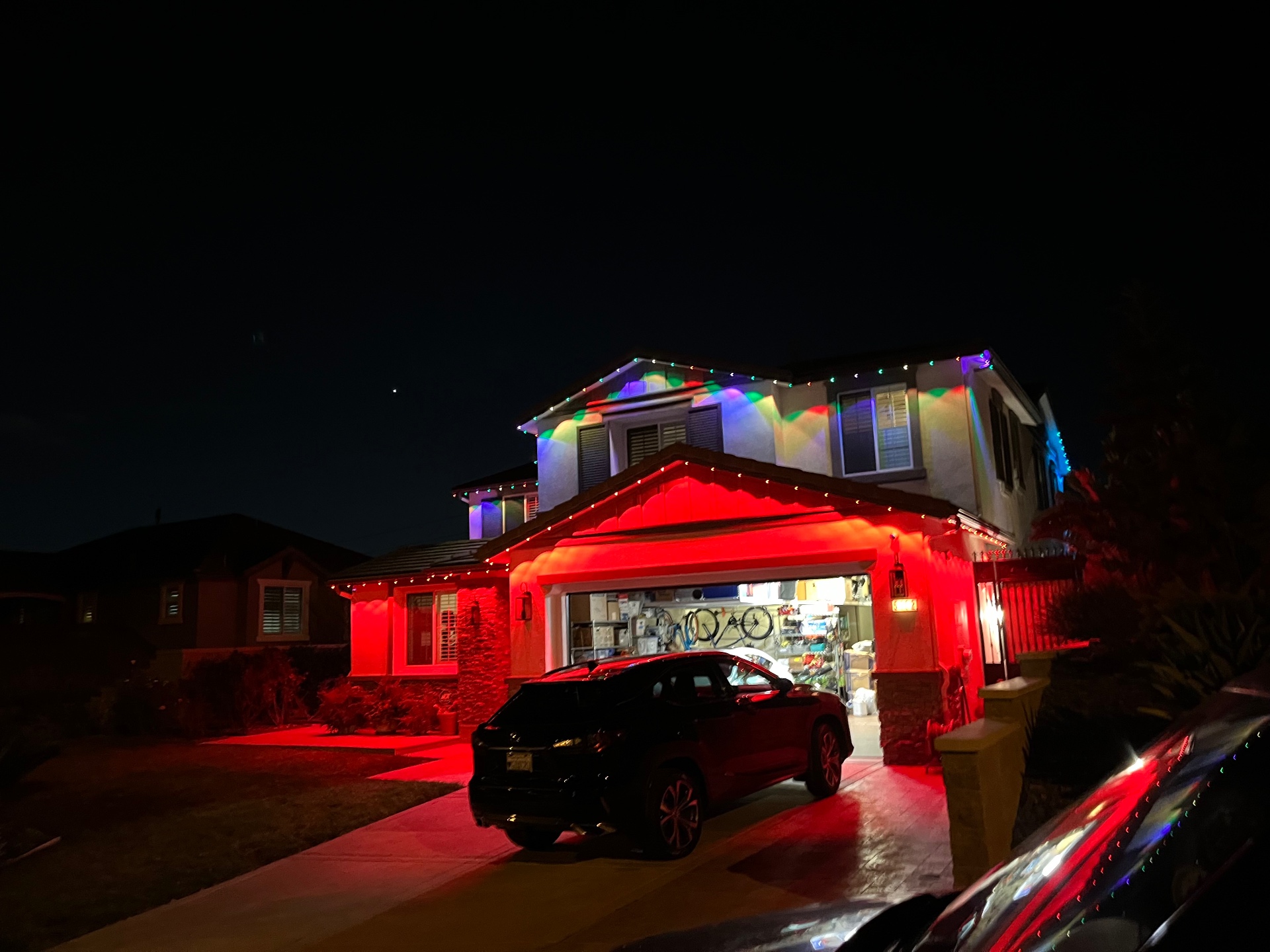 Colorful permanent holiday lighting installed beneath the fascia on a two-story home